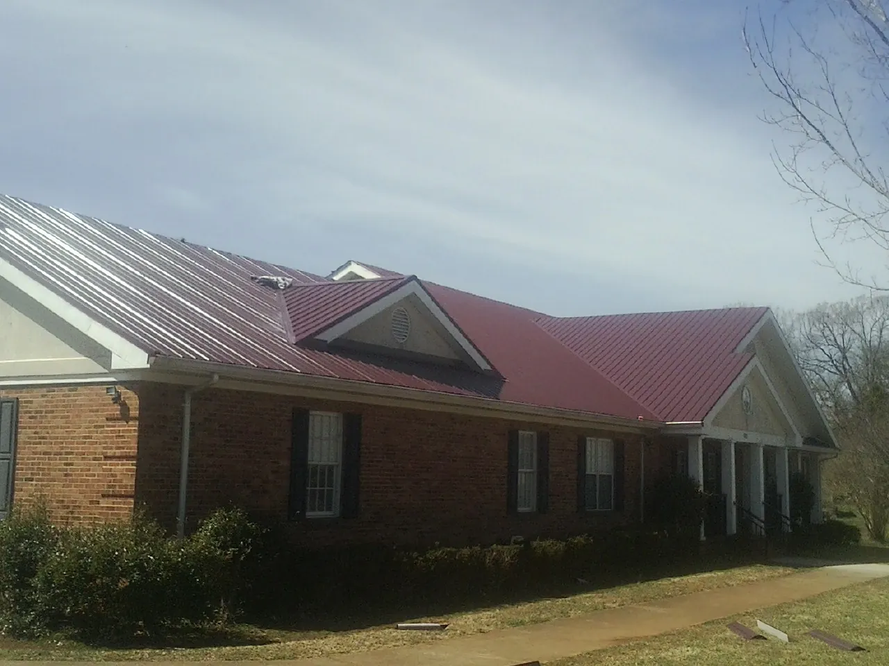 Red metal roof with gabled entries on a long brick building in Cambridge City