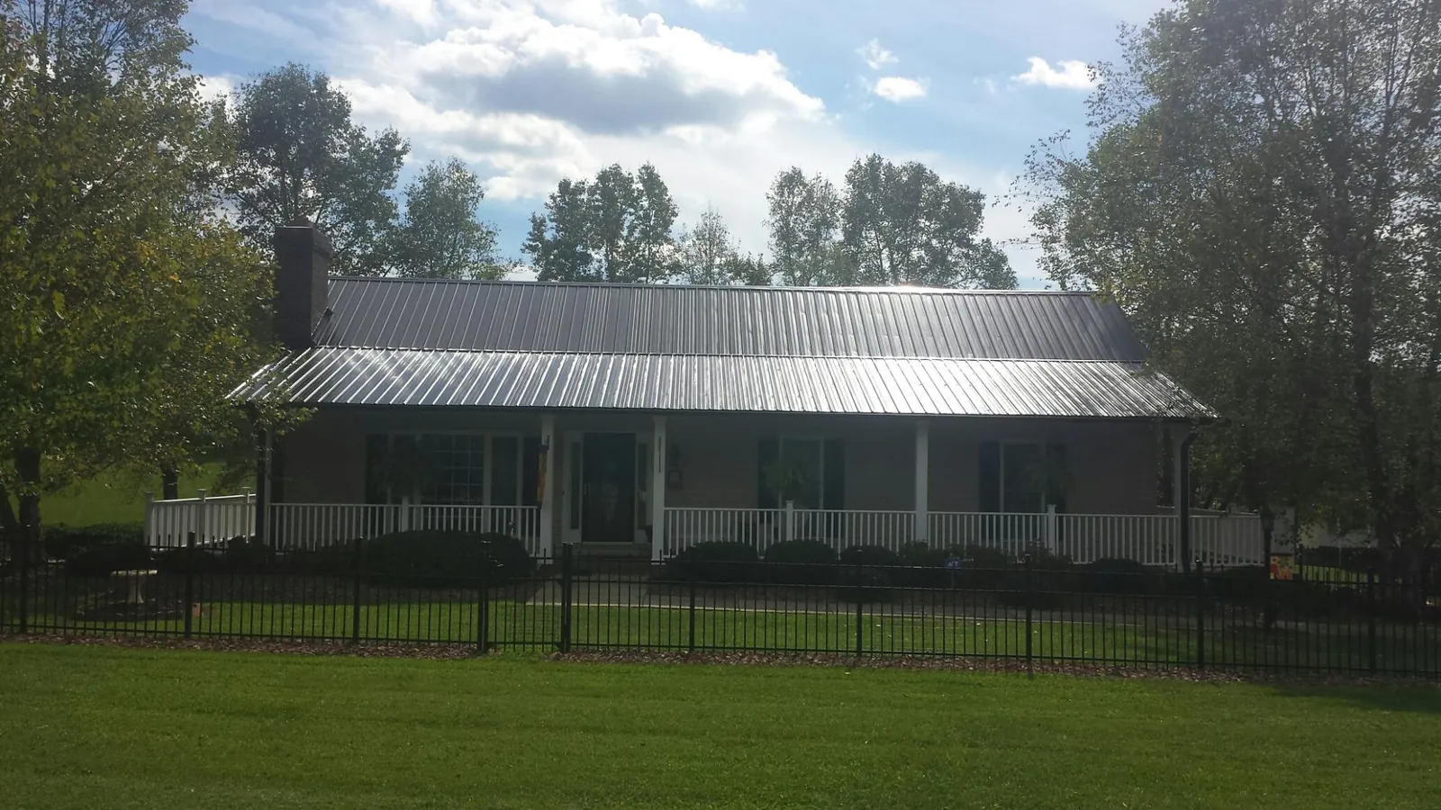 Gray metal roof on a brick ranch with a full width front porch — Gutter Guard Installation work by our crew in Cambridge City