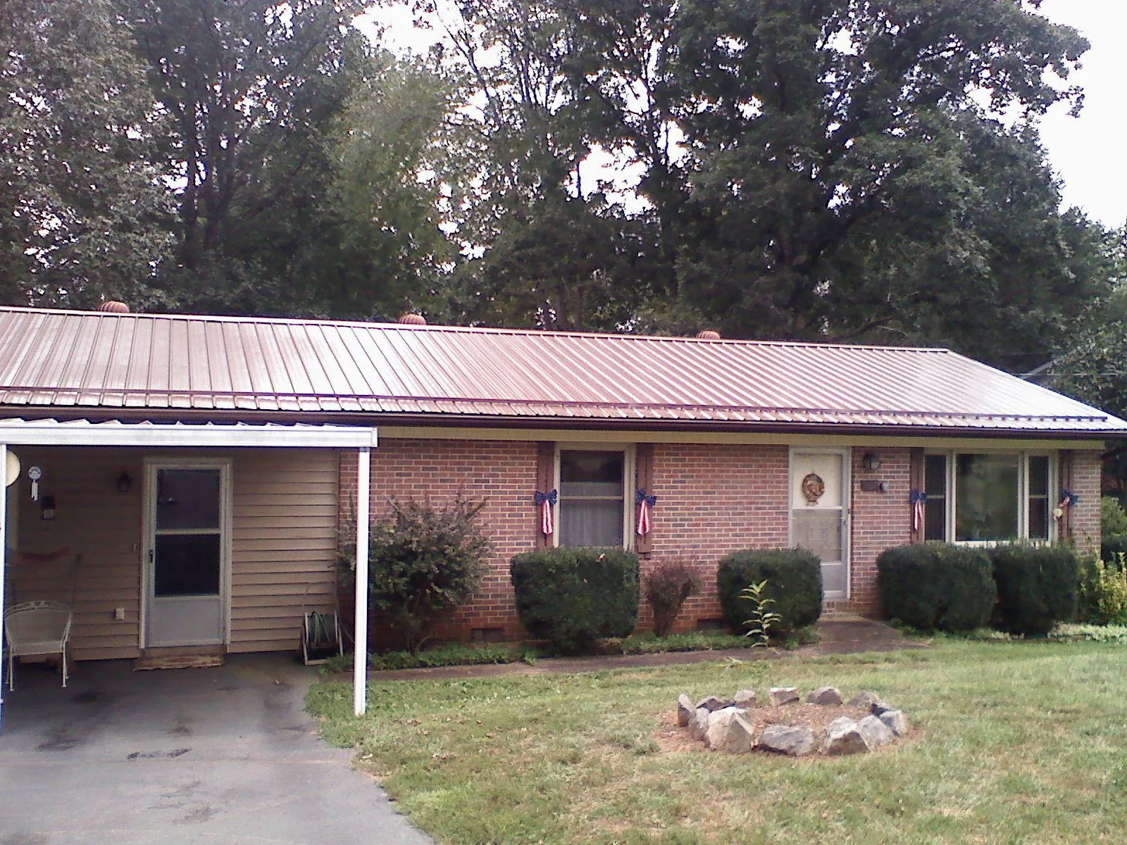 Bronze metal roof and carport on a brick ranch home — Roof Repair work by our crew in Cambridge City